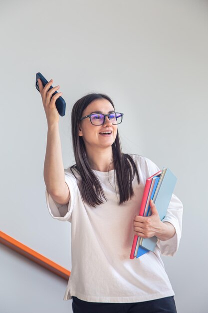 Mujer joven en gafas con teléfono inteligente y libretas