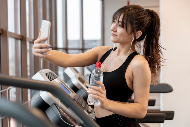 Mujer joven en el gimnasio tomando selfies