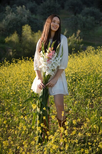 Mujer joven con gladiolos en la naturaleza.