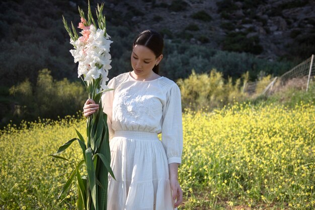 Mujer joven con gladiolos en la naturaleza.