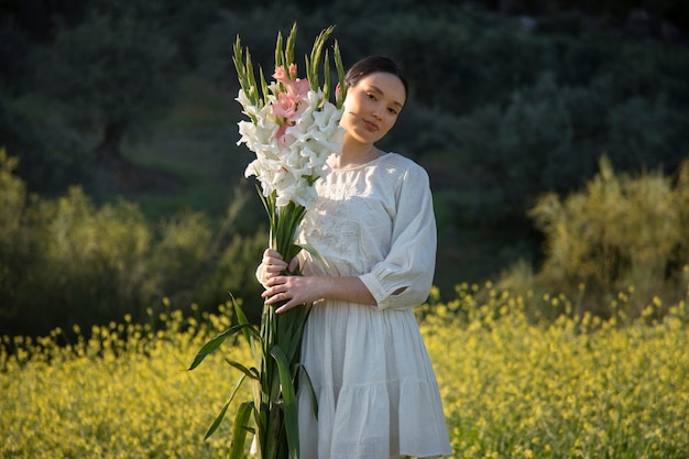 Foto gratuita mujer joven con gladiolos en la naturaleza.