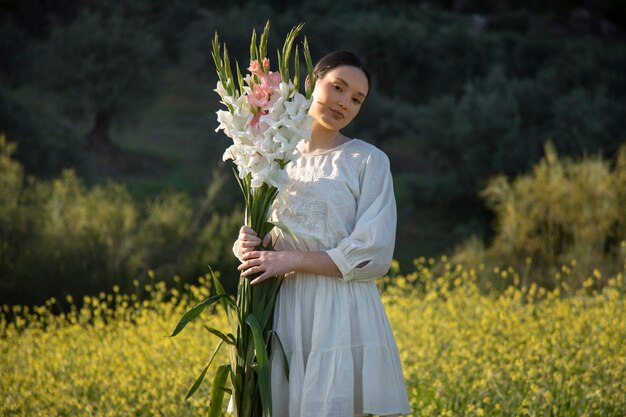 Mujer joven con gladiolos en la naturaleza.