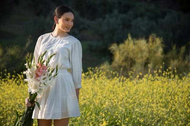 Foto gratuita mujer joven con gladiolos en la naturaleza.