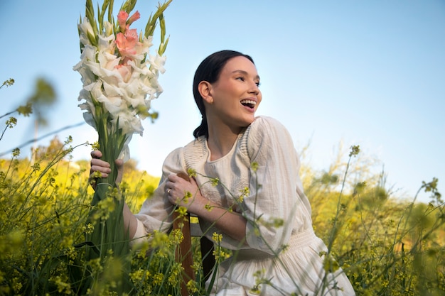 Mujer joven con gladiolos en la naturaleza.