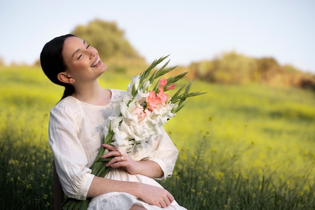 Foto gratuita mujer joven con gladiolos en la naturaleza.