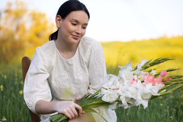 Mujer joven con gladiolos en la naturaleza.