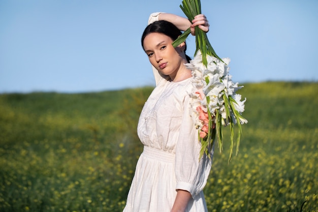 Mujer joven con gladiolos en la naturaleza.