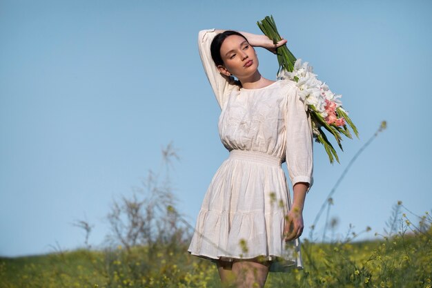 Mujer joven con gladiolos en la naturaleza.