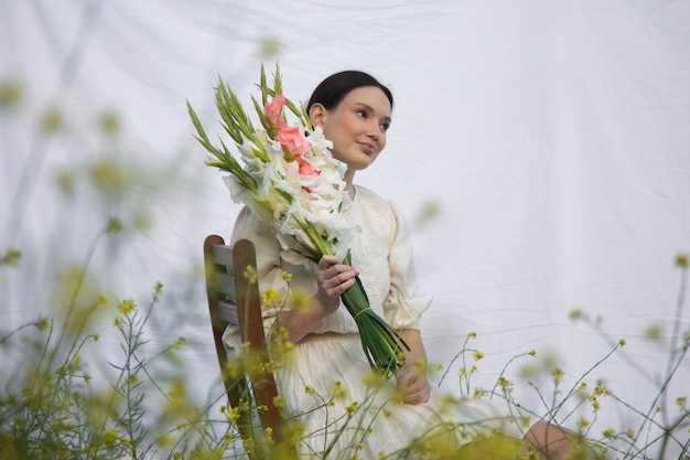 Mujer joven con gladiolos en la naturaleza.