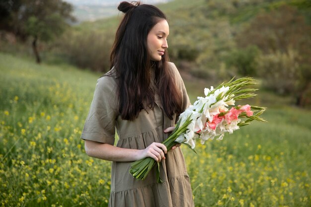 Mujer joven con gladiolos en la naturaleza.