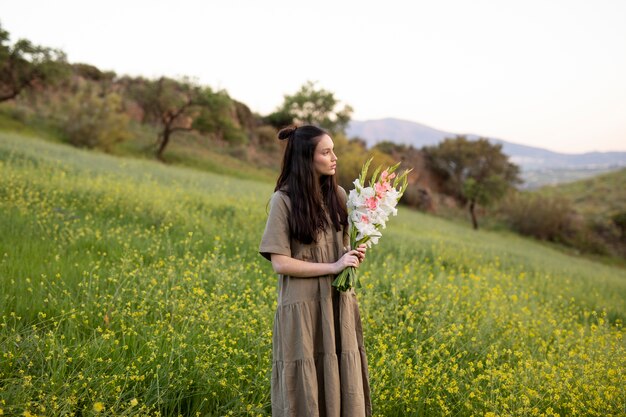 Mujer joven con gladiolos en la naturaleza.