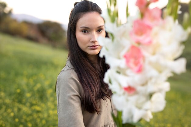 Mujer joven con gladiolos en la naturaleza.