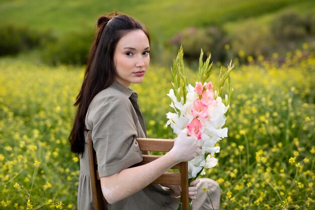 Mujer joven con gladiolos en la naturaleza.