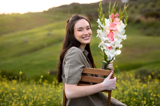 Mujer joven con gladiolos en la naturaleza.