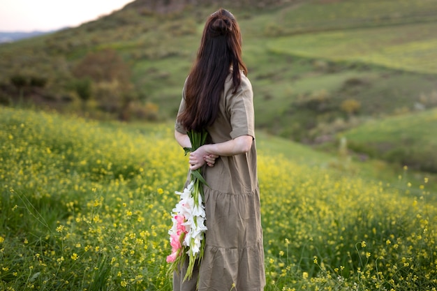 Mujer joven con gladiolos en la naturaleza.