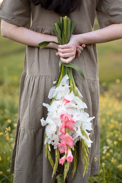 Mujer joven con gladiolos en la naturaleza.