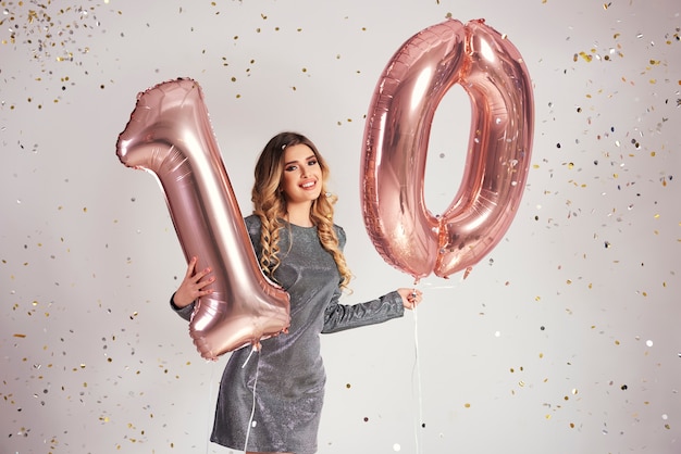 Mujer joven con globos en forma de 10