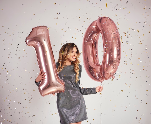 Mujer joven con globos en forma de 10