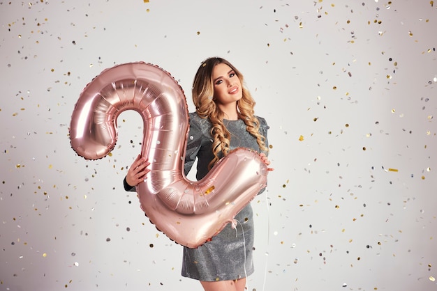 Mujer joven con globos en forma de dos