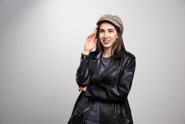 Mujer joven con gorra y chaqueta de cuero negro.