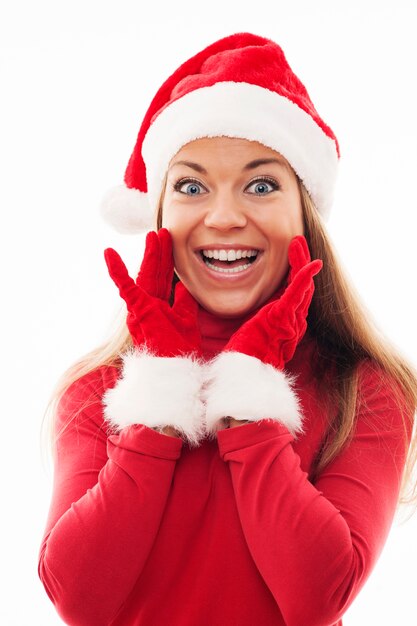 Mujer joven con gorro de Papá Noel y guantes mirando emocionado