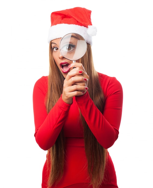 Mujer joven con un gorro de santa claus y una lupa