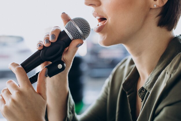 Mujer joven grabando voz actuando en el estudio