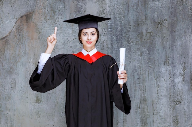Mujer joven graduada en bata con diploma universitario. foto de alta calidad
