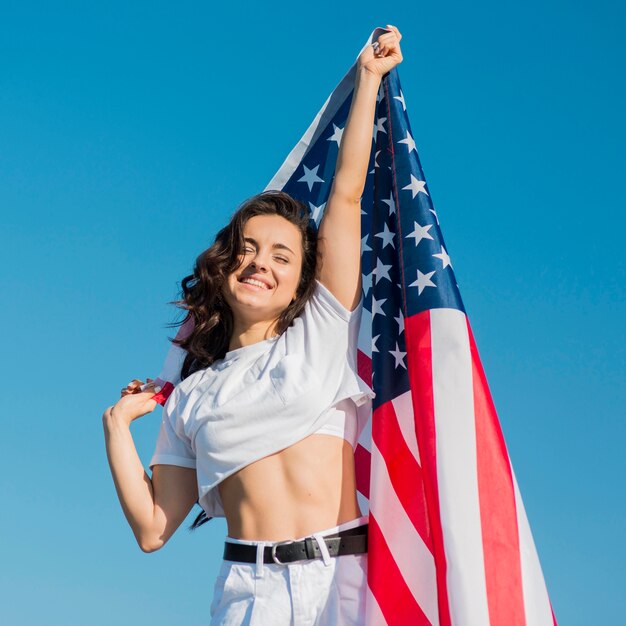 Mujer joven con gran bandera de Estados Unidos