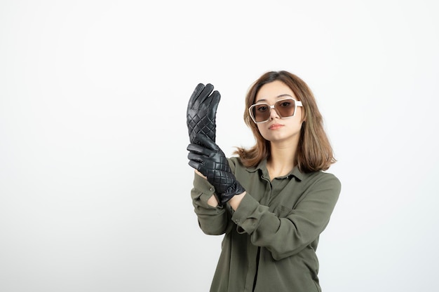 Mujer joven con guantes negros y anteojos posando y de pie. foto de alta calidad