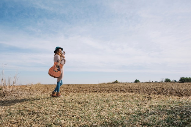 Mujer joven con guitarra en el campo