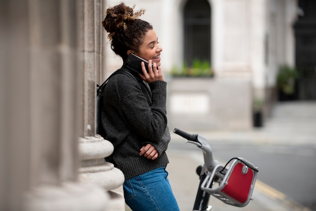 Foto gratuita mujer joven hablando por su teléfono inteligente en la ciudad