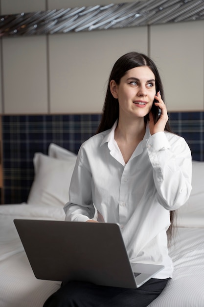 Mujer joven hablando por su teléfono inteligente en una habitación de hotel