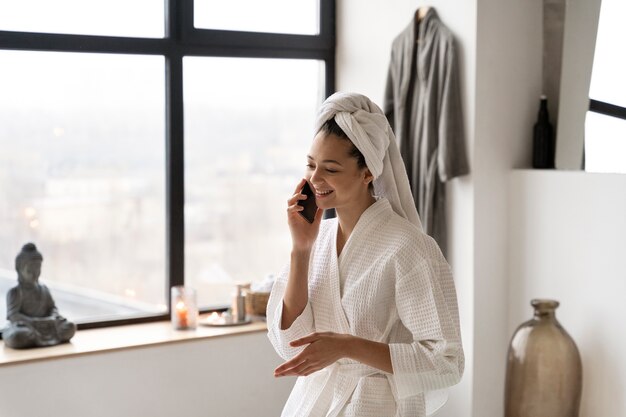 Mujer joven hablando por teléfono antes de tomar un baño