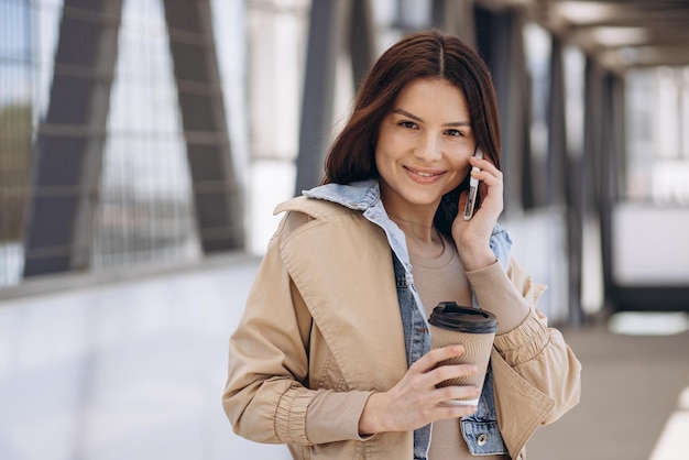 Mujer joven hablando por teléfono y bebiendo café