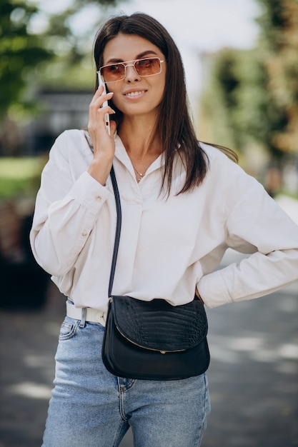 Foto gratuita mujer joven hablando por teléfono fuera de la calle
