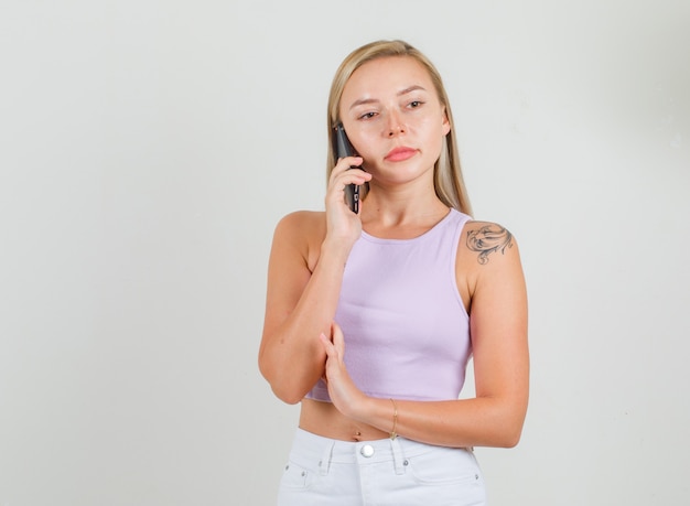 Mujer joven hablando por teléfono inteligente en camiseta