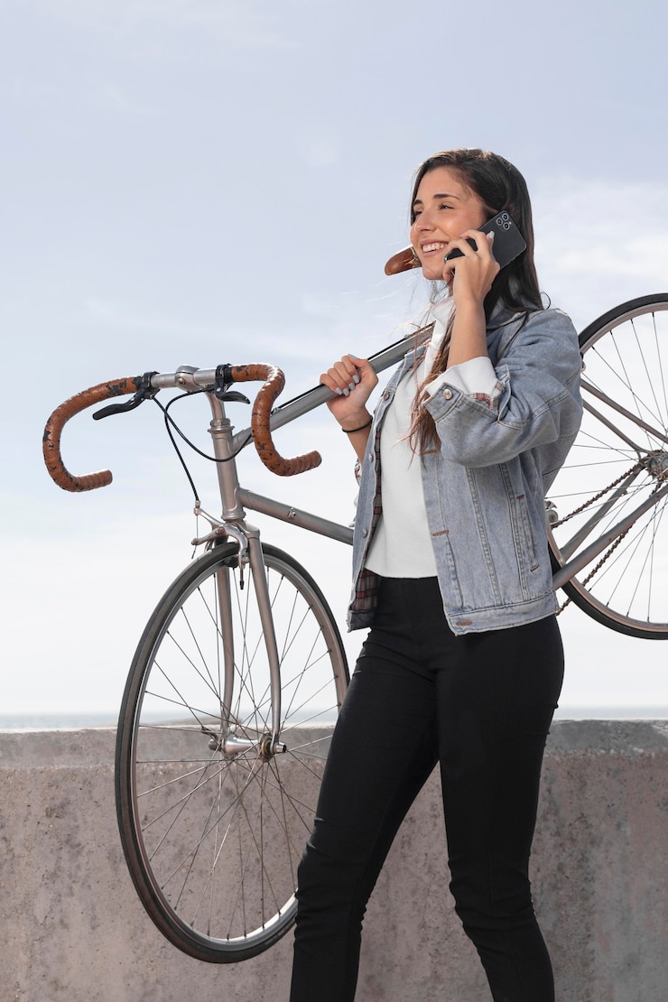 Foto gratuito mujer joven hablando por teléfono junto a una bicicleta