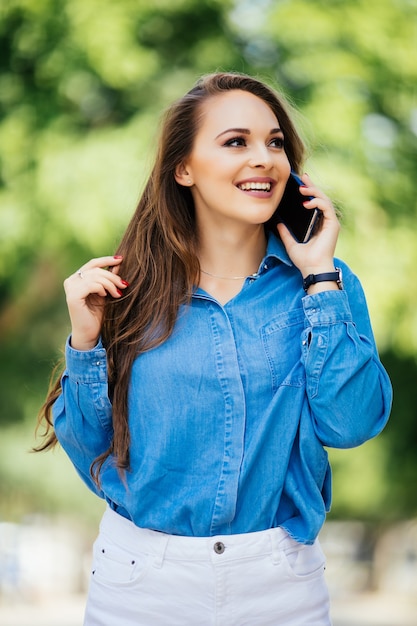 Mujer joven hablando por teléfono móvil en la calle de verano