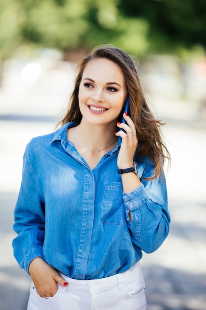 Mujer joven hablando por teléfono móvil en la calle de verano