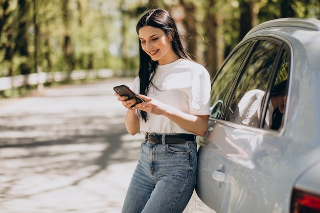 Mujer joven hablando por teléfono por su coche electro