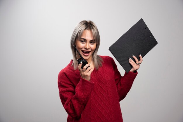 Foto gratuita mujer joven hablando con transceptor de radio sobre fondo gris.