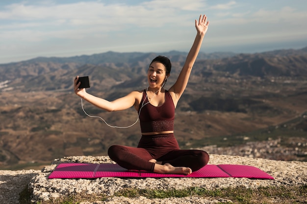 Mujer joven hablando videollamada mientras hace yoga