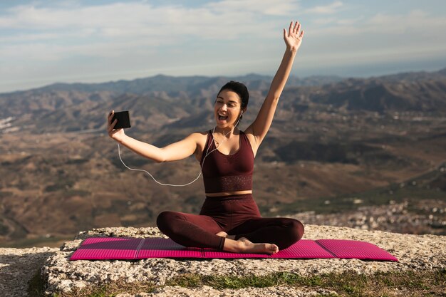 Mujer joven hablando videollamada mientras hace yoga