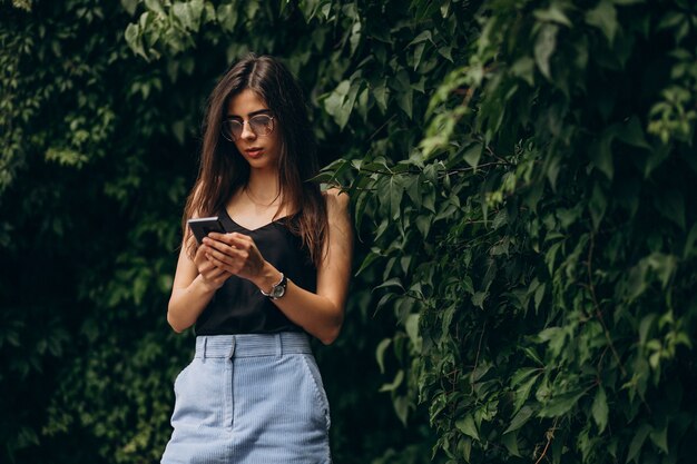 Mujer joven, hablar teléfono, en el estacionamiento