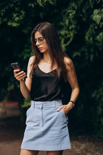 Mujer joven, hablar teléfono, en el estacionamiento