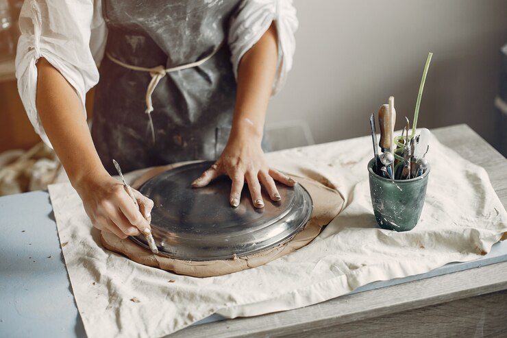 Foto gratuito mujer joven hace cerámica en el taller