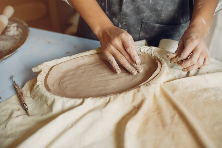 Foto gratuito mujer joven hace cerámica en el taller