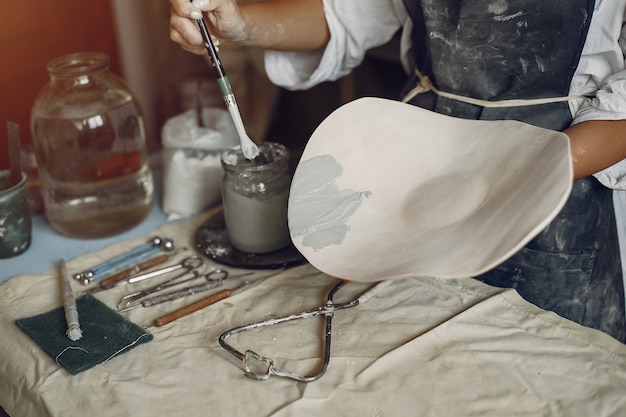 Foto gratuita mujer joven hace cerámica en taller