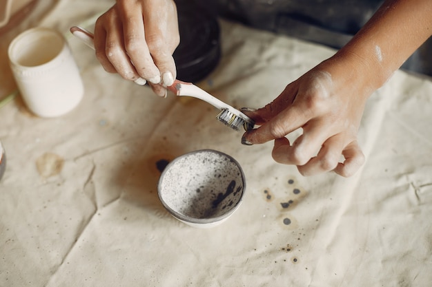 Foto gratuita mujer joven hace cerámica en taller